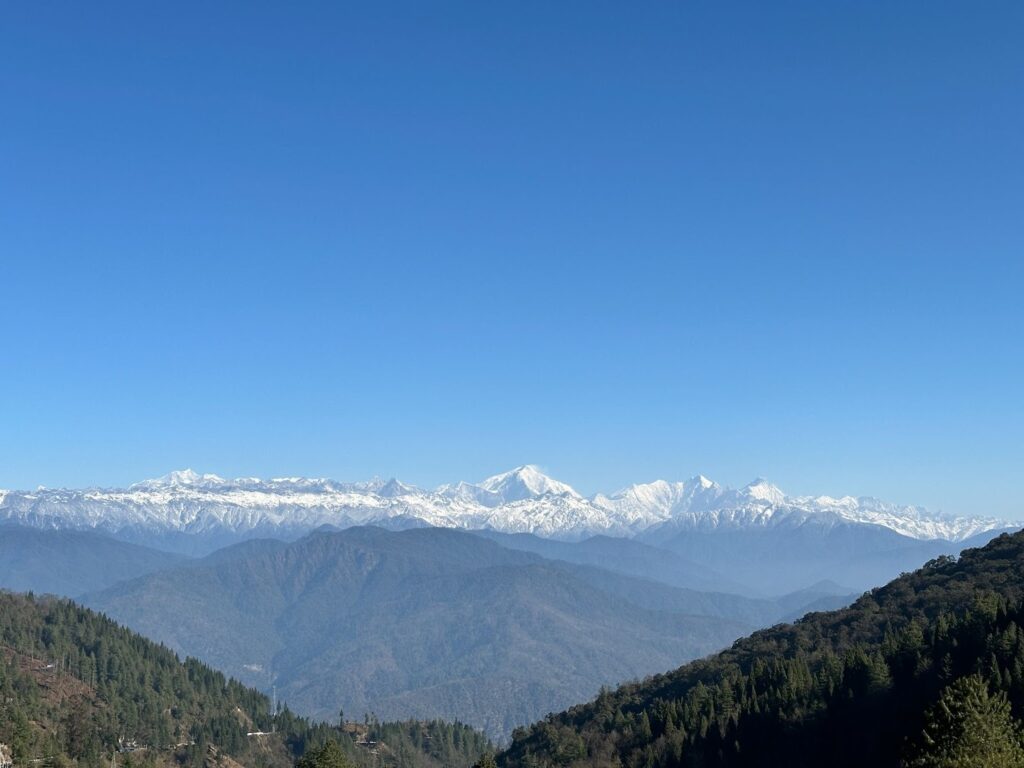 Snow-capped Himalayan range seen from Bomdila Pass, Arunachal Pradesh, under a clear blue sky with layered green ridges in the foreground by Tawang Tours.