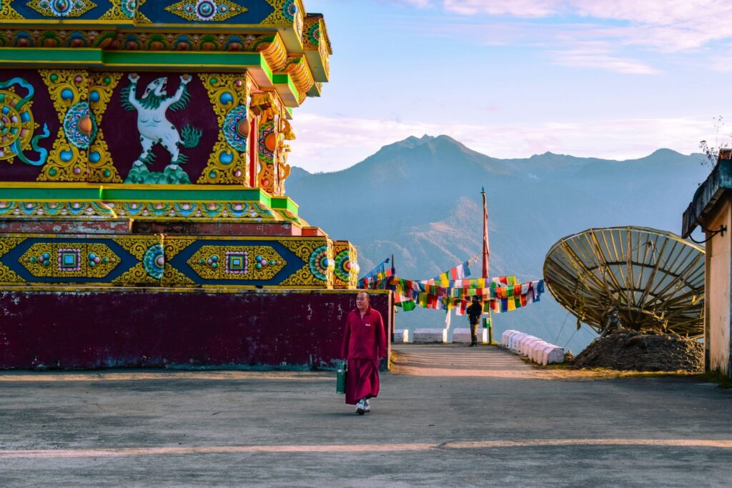 Prayer flags and a monk in warm monastery light inside Tawang Monastery, Arunachal Pradesh.