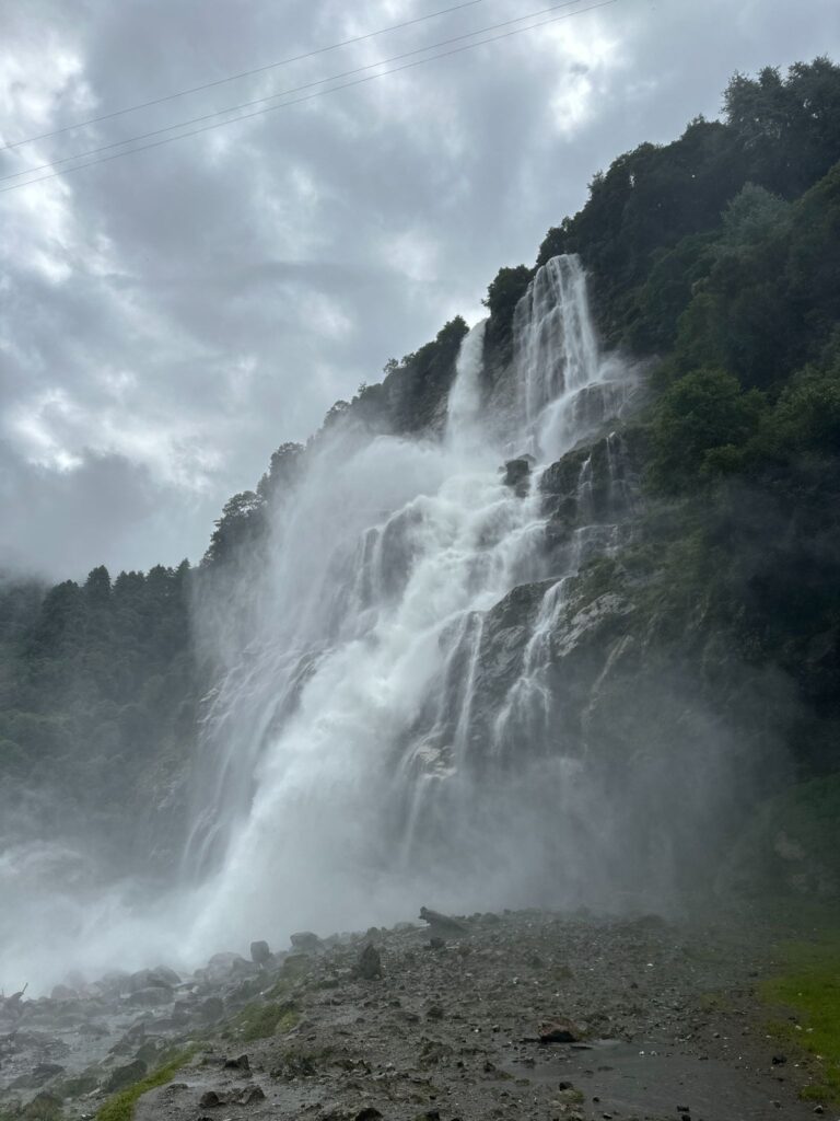 Nuranang (Jung) Waterfall dropping into a rocky pool with mist spray.